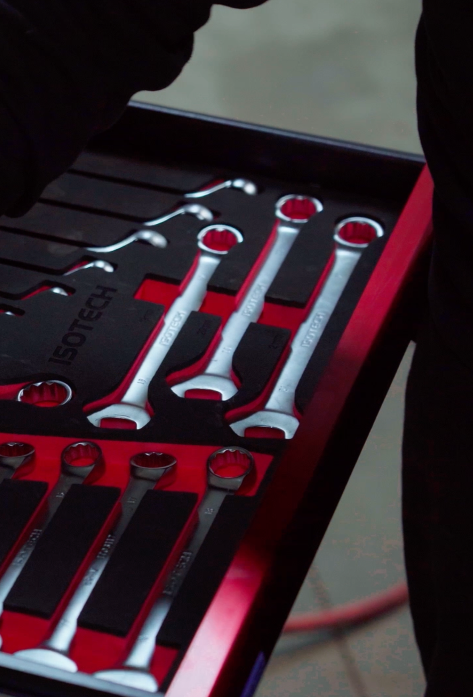 Une boîte à outils contenant des clés à œil avec des poignées rouges et une boîte noire et rouge