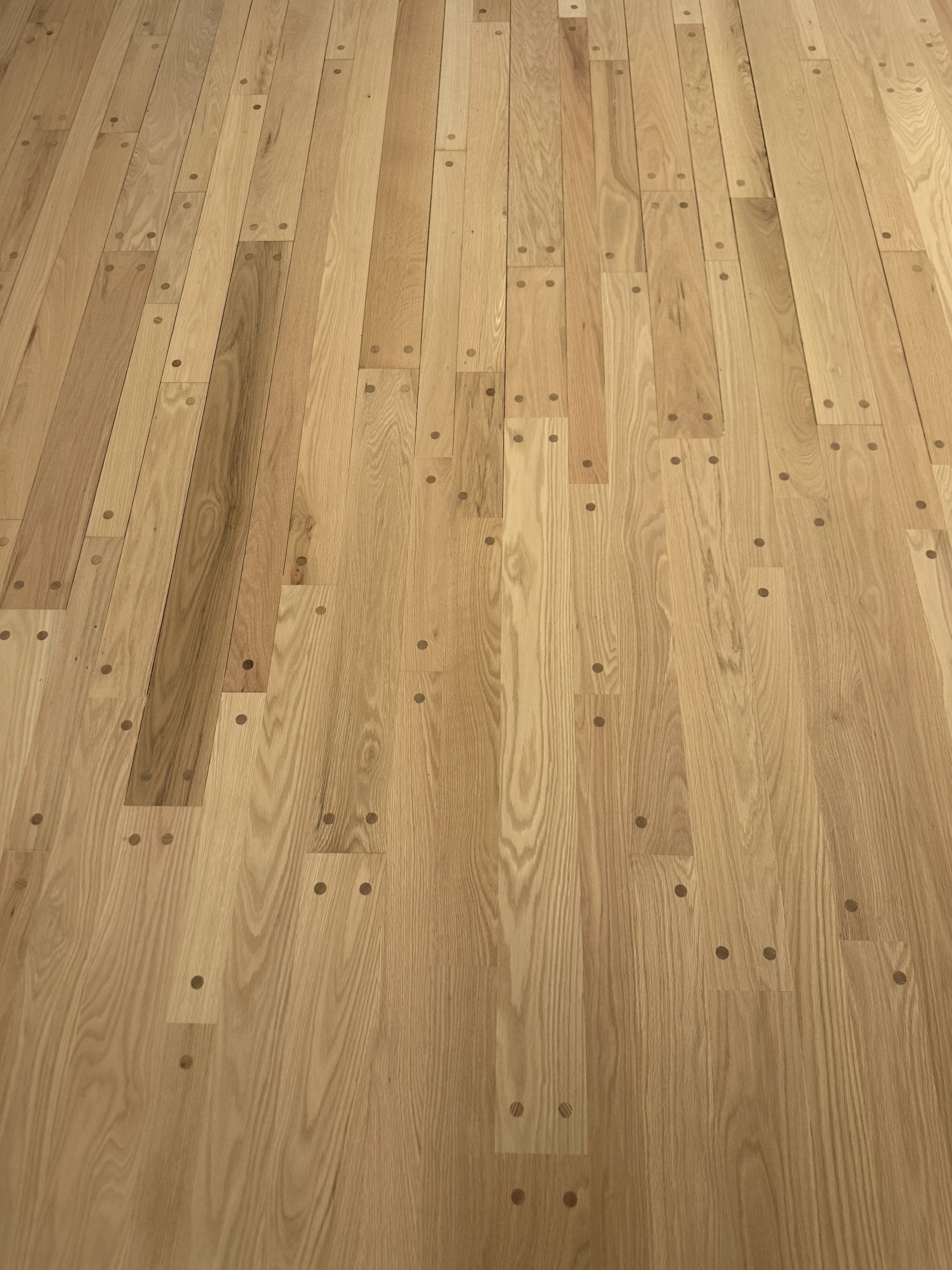 A wooden floor with a pattern of evenly spaced small holes.