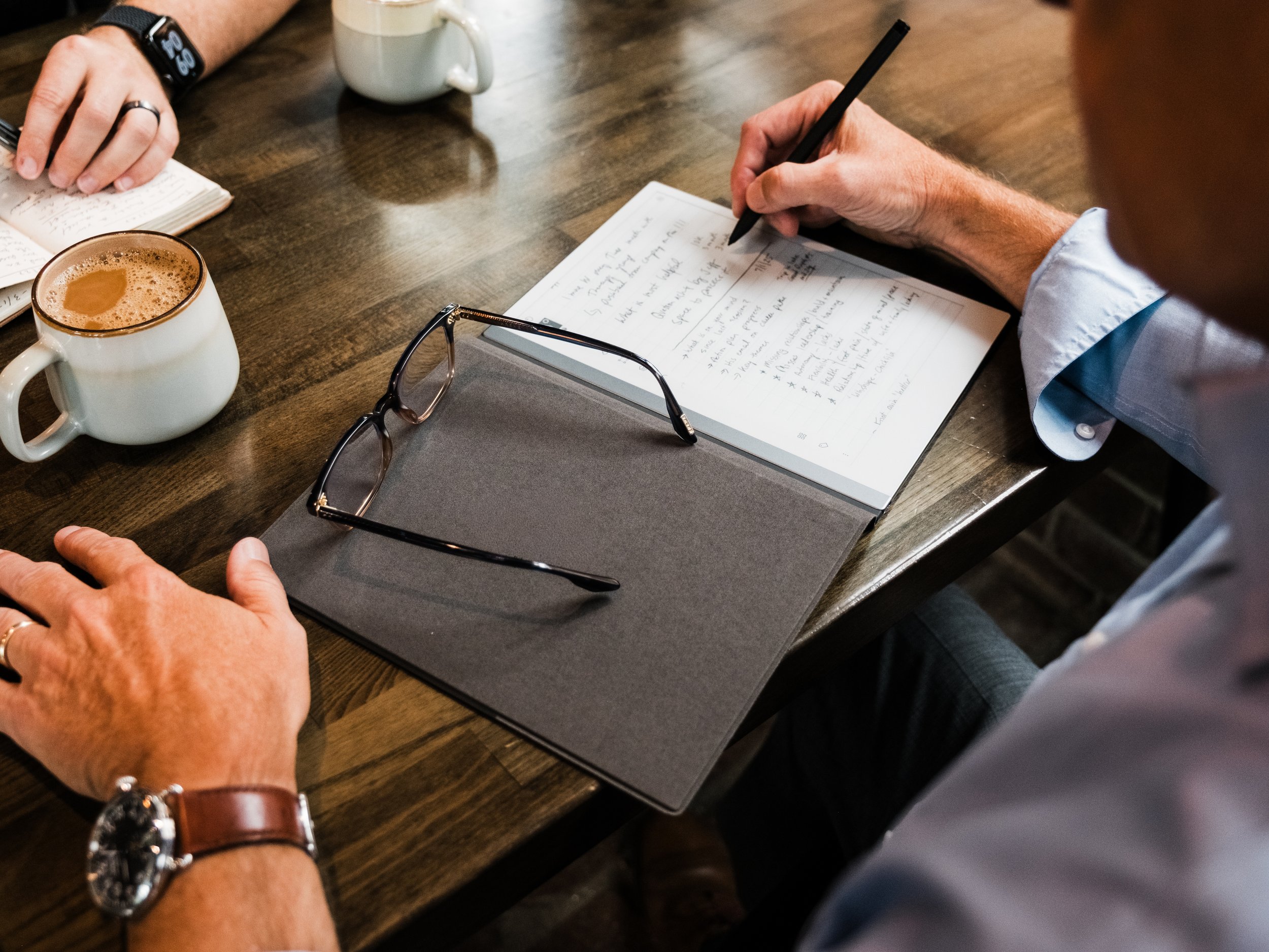 Executive coaching session with Jeff Fry talking notes, journal, and coffee during a career planning conversation.