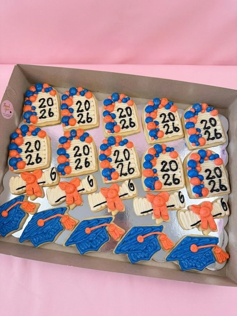 Decorated cookies in a box with graduation theme and the year 2026, including diplomas and mortarboard caps.