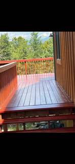View from a wooden balcony overlooking trees and a clear sky.