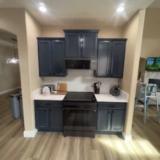 Kitchen with dark blue cabinets, black stove, and white countertops