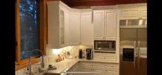 Kitchen with white cabinets, a window, and stainless steel appliances, including a microwave and oven.