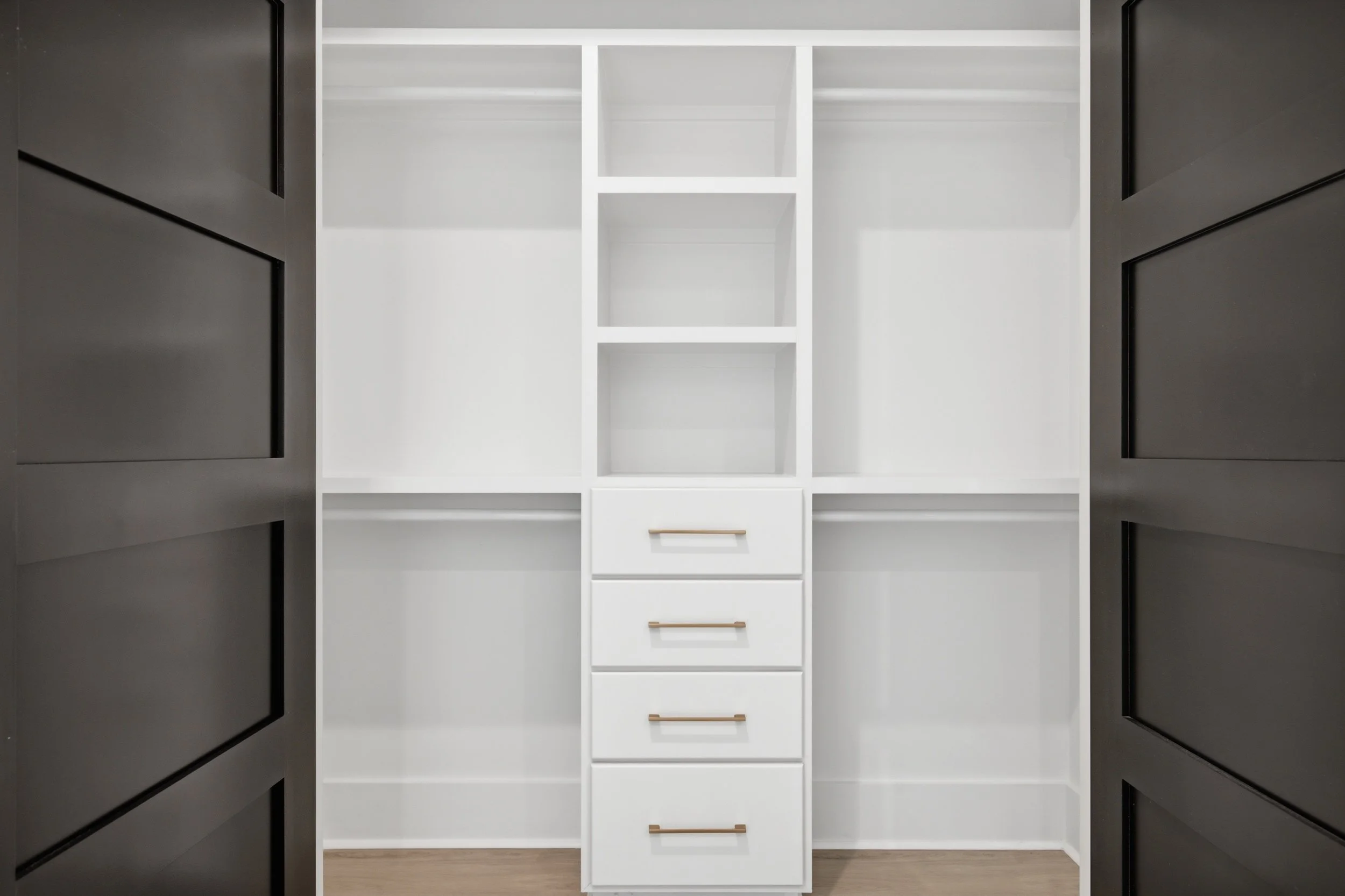 View of an empty white closet with shelving and drawers, photo taken from the open door.