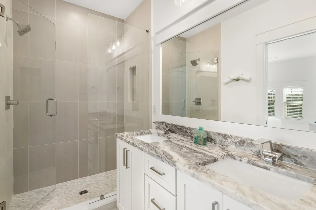 Modern bathroom with a glass-enclosed shower and a marble countertop double sink vanity.