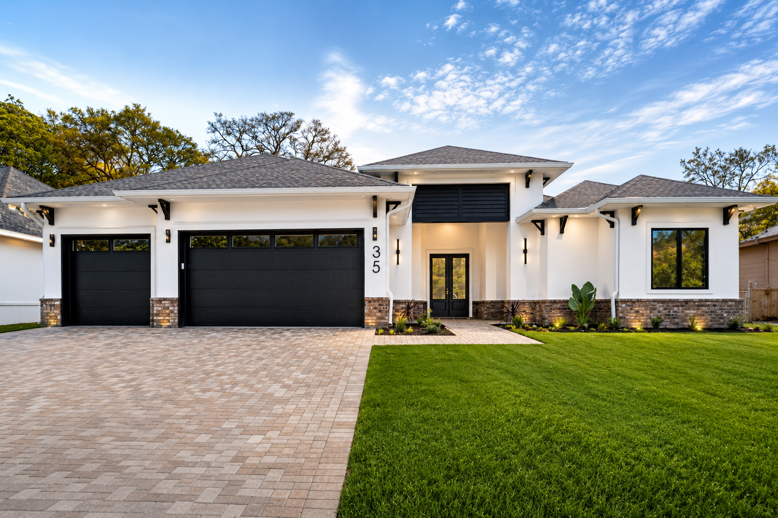 Modern custom house in Northwest Florida with white stucco exterior, black three car garage doors, and landscaped front yard