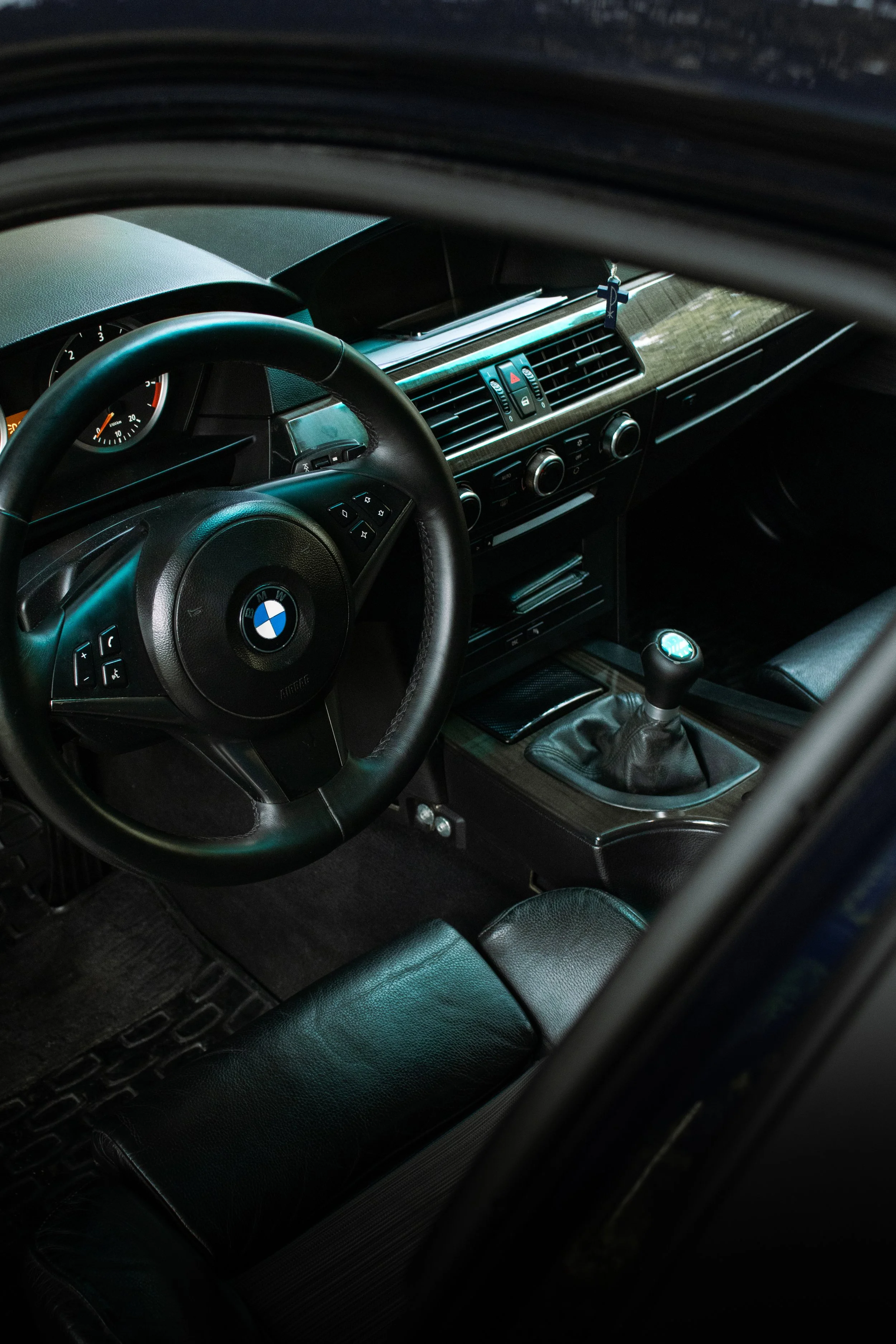 Profesionalna fotografija interijera BMW e60 koja prikazuje detalje mjenjača, kožnih sjedala i kontrolne ploče, snimljena visokim bočnim kutom.