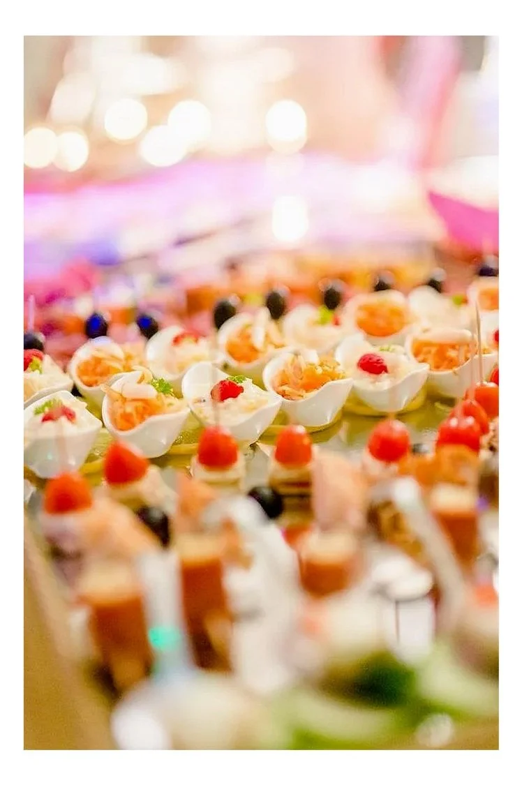 Verschiedene kleine, dekorativ angerichtete Häppchen und Canapés auf einer Buffetplatte, serviert bei einer festlichen Veranstaltung.
