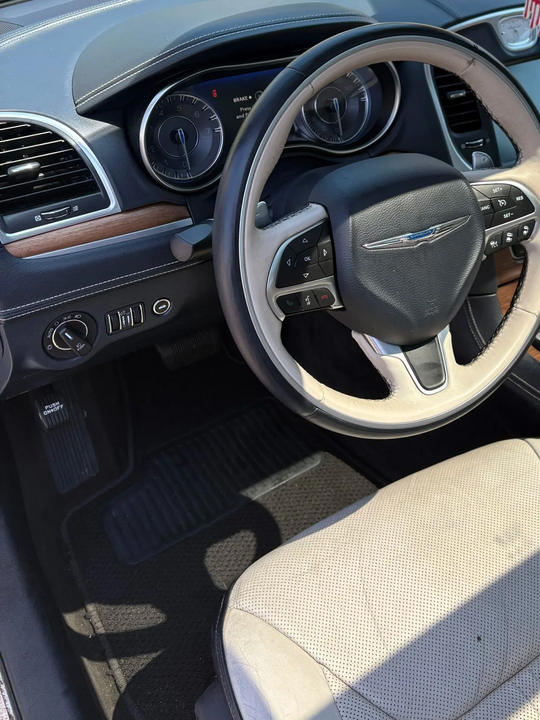 Interior of a car showing the steering wheel, dashboard, air vents, and a beige seat.