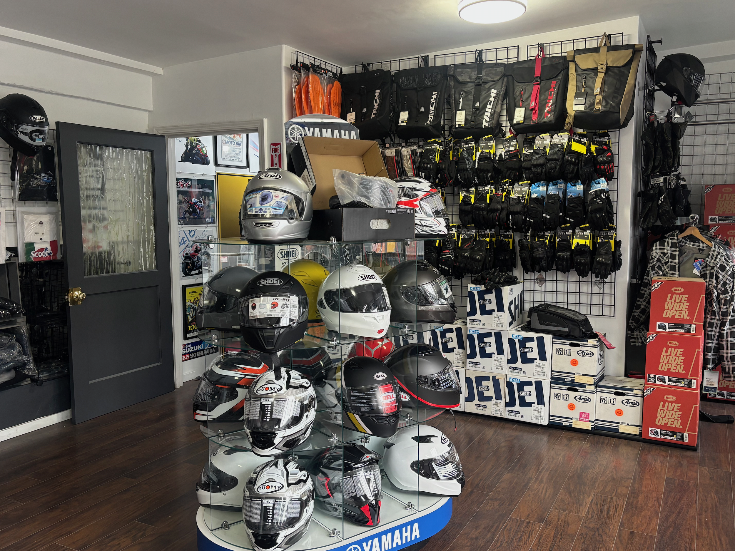 Display of motorcycle helmets, gloves, motorcycle bags, and gear in a motorcycle shop with Yamaha branding.