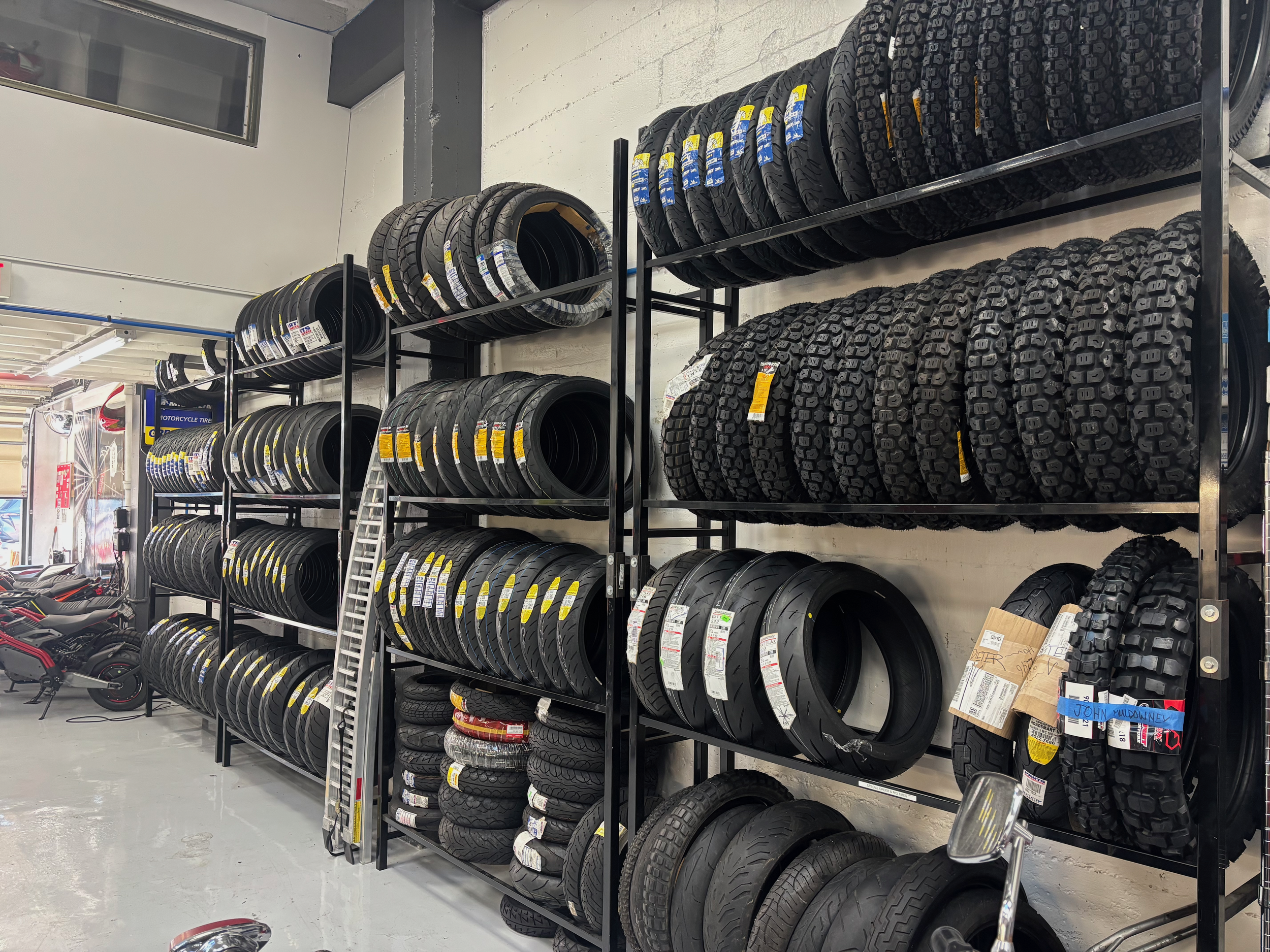 Stacked shelves of various tires and rims inside a tire shop or warehouse.