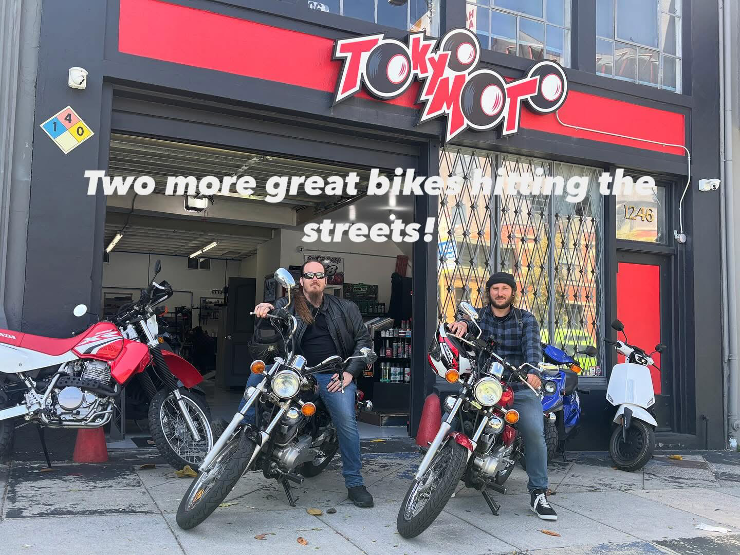 Two motorcyclists sitting on their bikes in front of a motorcycle shop called Tokyo Moto. The shop has a red and black sign and a large window, with motorcycles and a scooter displayed outside. The text on the image reads, 'Two more great bikes riding the streets!'