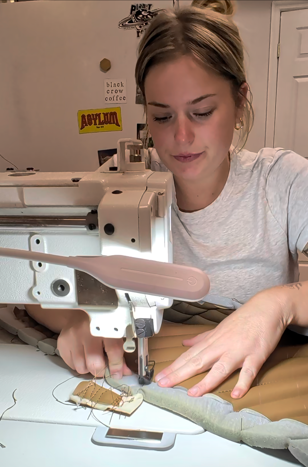 A woman is sewing with a sewing machine, working on a piece of fabric or material.