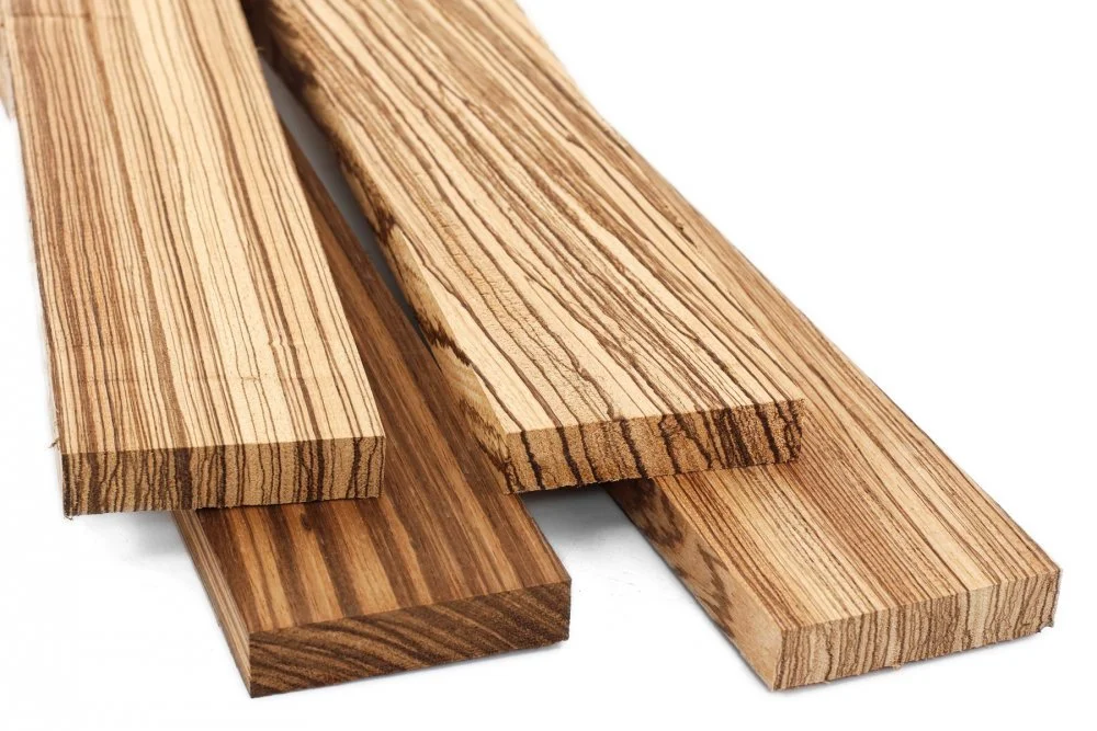 Three pieces of striped wood, two are lighter and one is darker, laid parallel on a white background.