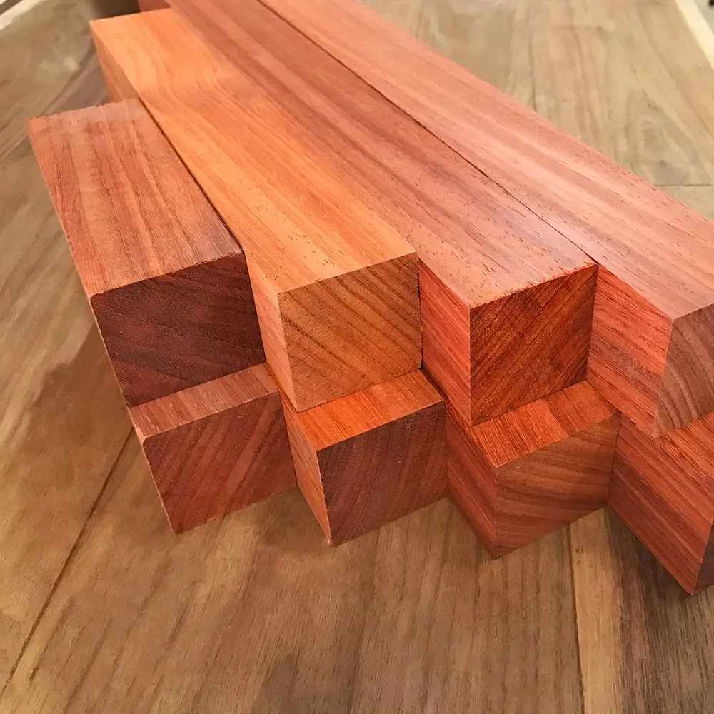 Several pieces of polished reddish wood with visible grain, arranged on a wooden surface.
