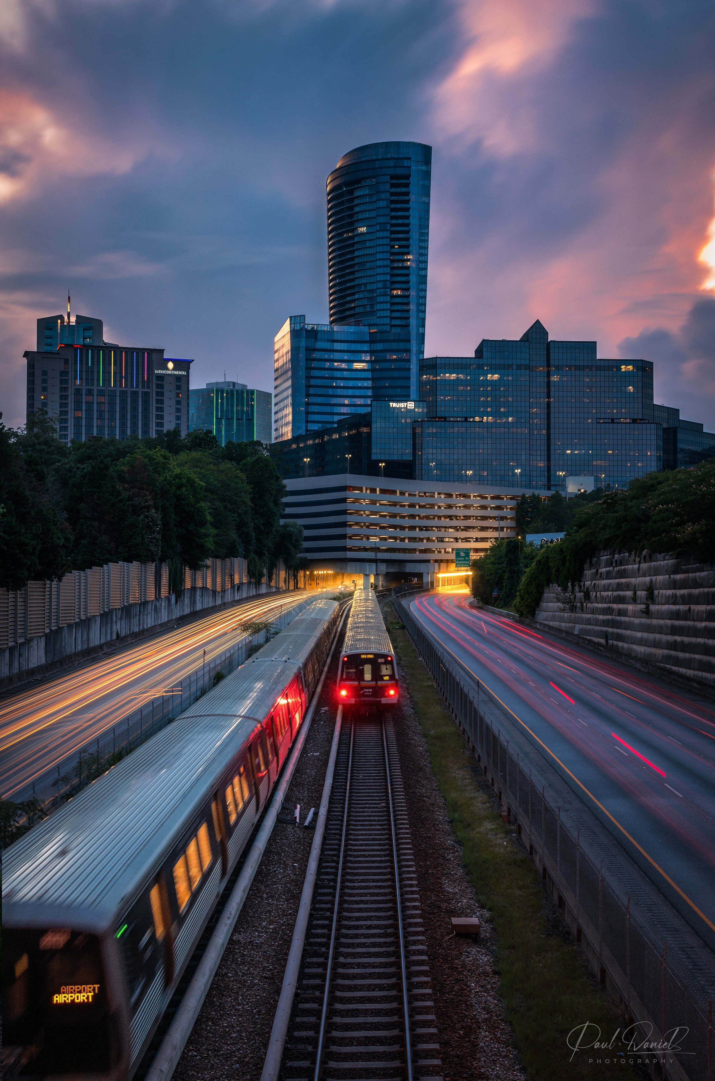 MARTA train and highway traffic motion blur beneath the Buckhead skyline, Sovereign building, and Atlanta Financial Center at dusk in Atlanta, GA