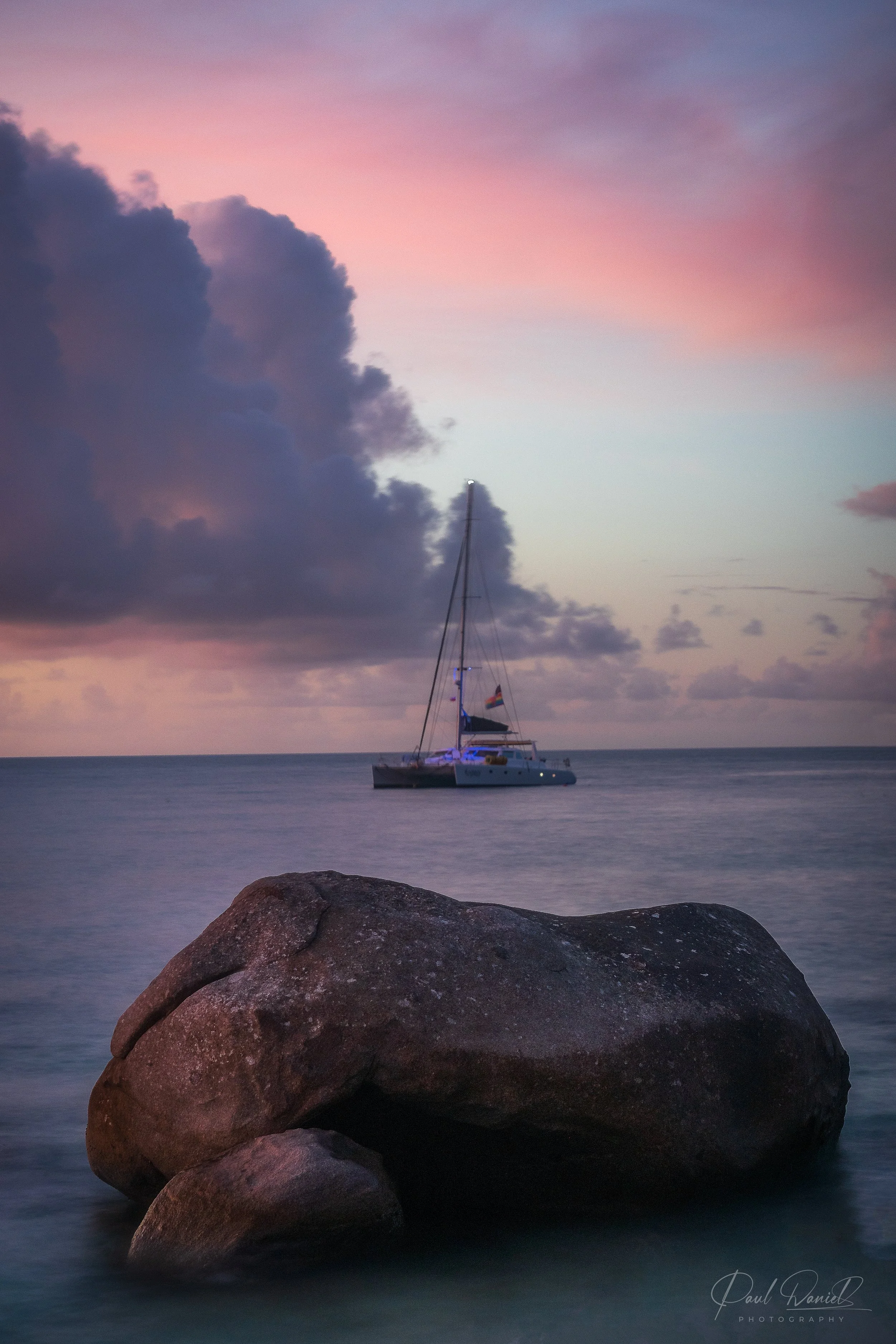 Sunset seascape of anchored sailboat near the iconic granite boulders of The Baths on Virgin Gorda, British Virgin Islands
