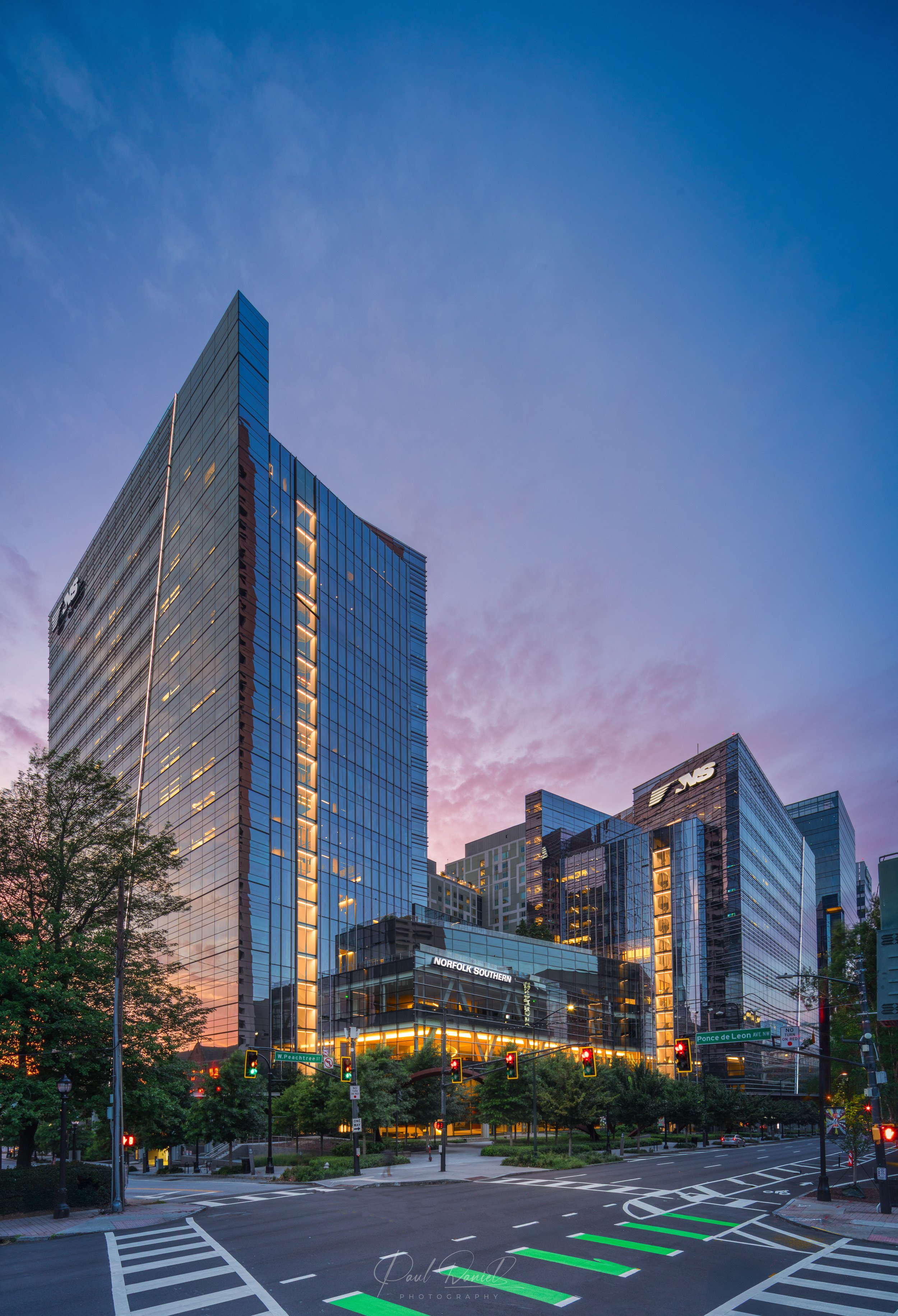 Modern architectural twilight view of the Norfolk Southern Headquarters campus featuring illuminated glass curtain walls at Spring Street in Midtown Atlanta, GA 