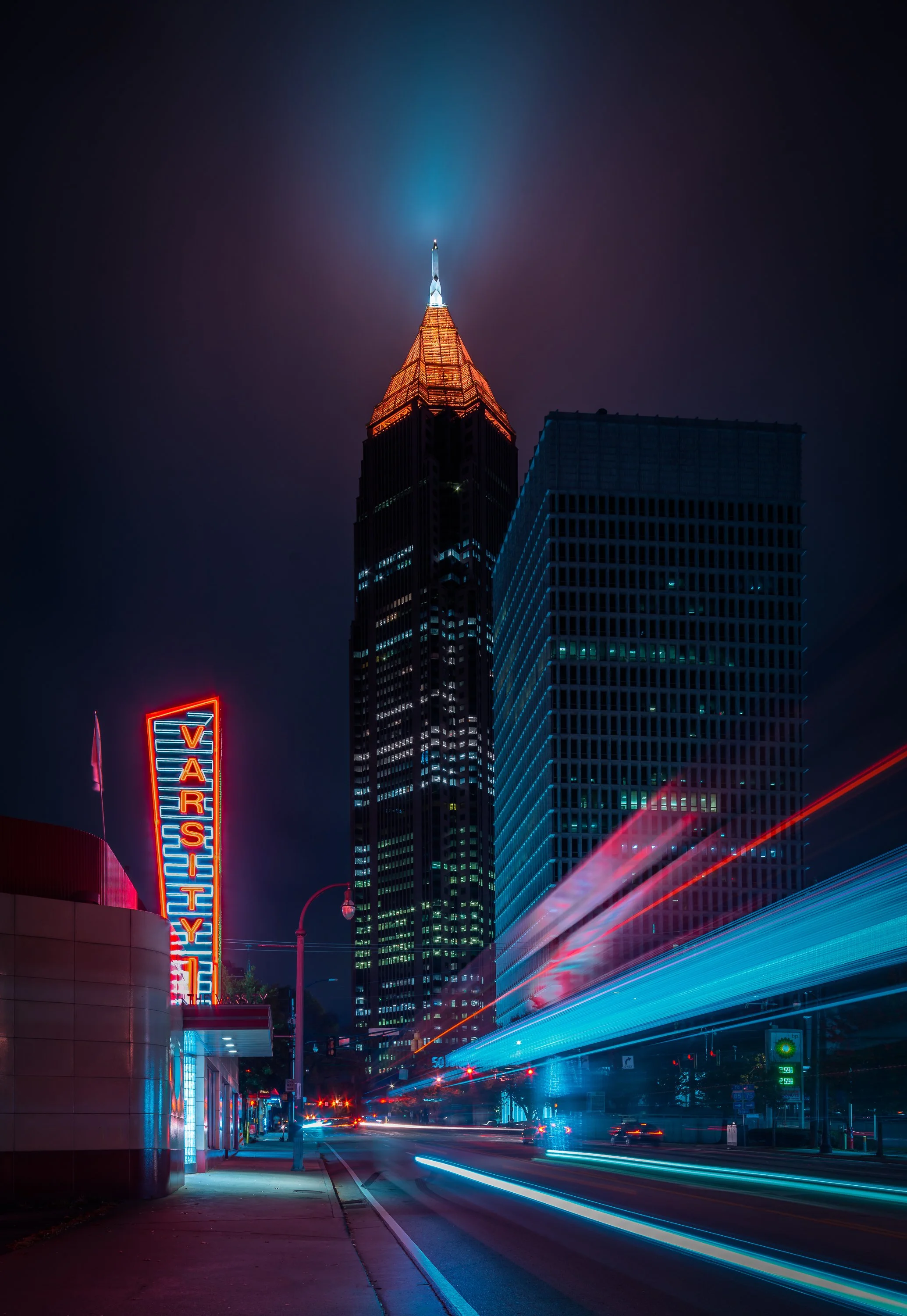 The Varsity neon sign and Bank of America Plaza spire at night with long-exposure traffic motion blur in Midtown Atlanta