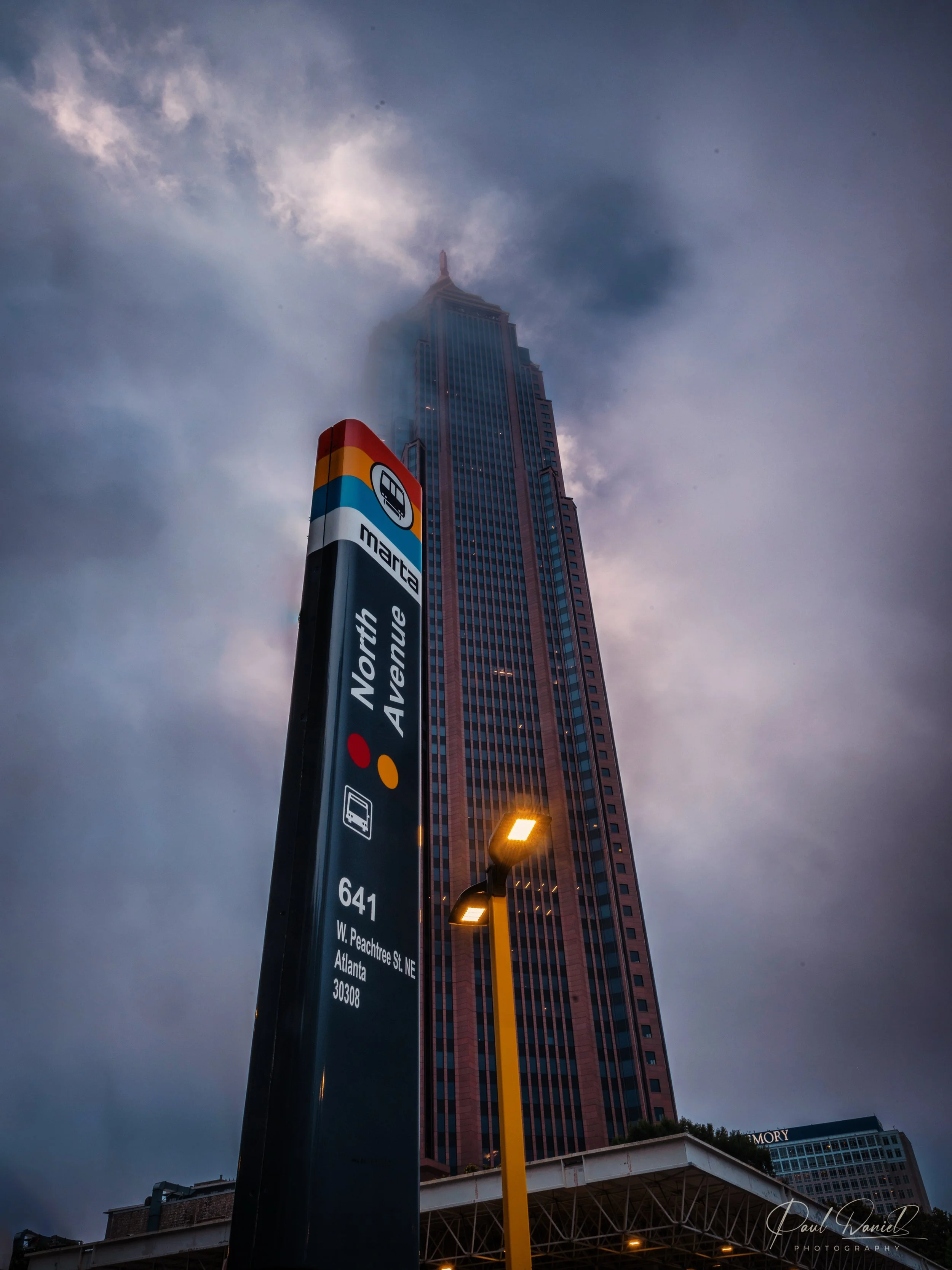North Avenue MARTA transit sign and Bank of America Plaza skyscraper under dramatic stormy clouds in Midtown Atlanta