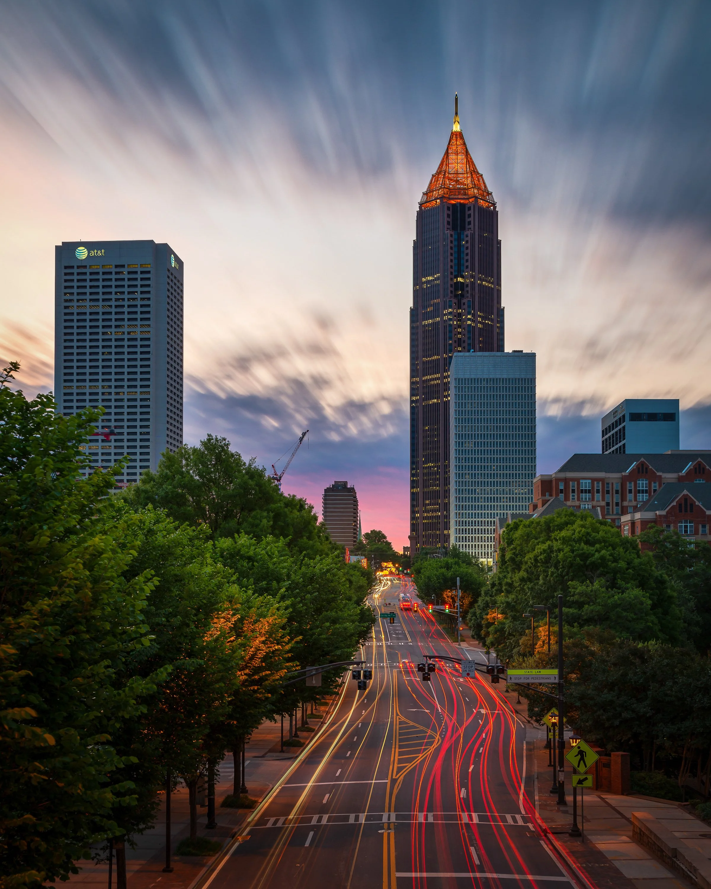 Sunrise over midtown Atlanta featuring the glowing spire of Bank of America Plaza and long exposure traffic light trails.
