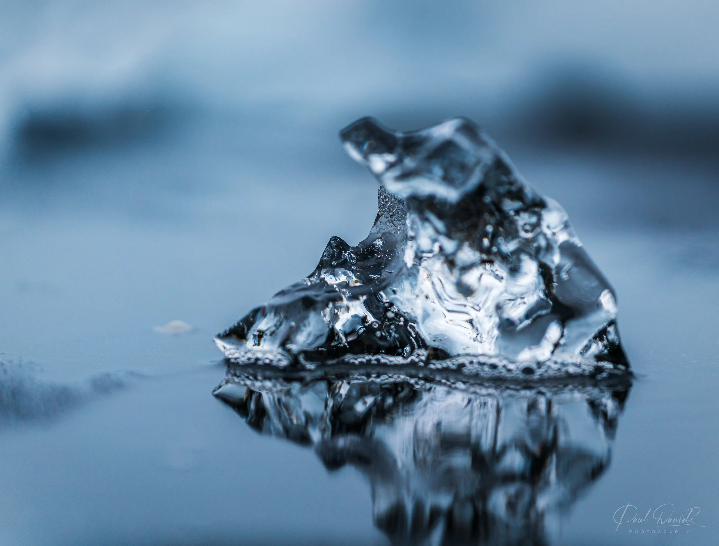 Close-up landscape photograph of crystalline glacial ice formation glistening on the shores of Diamond Beach in Iceland. 