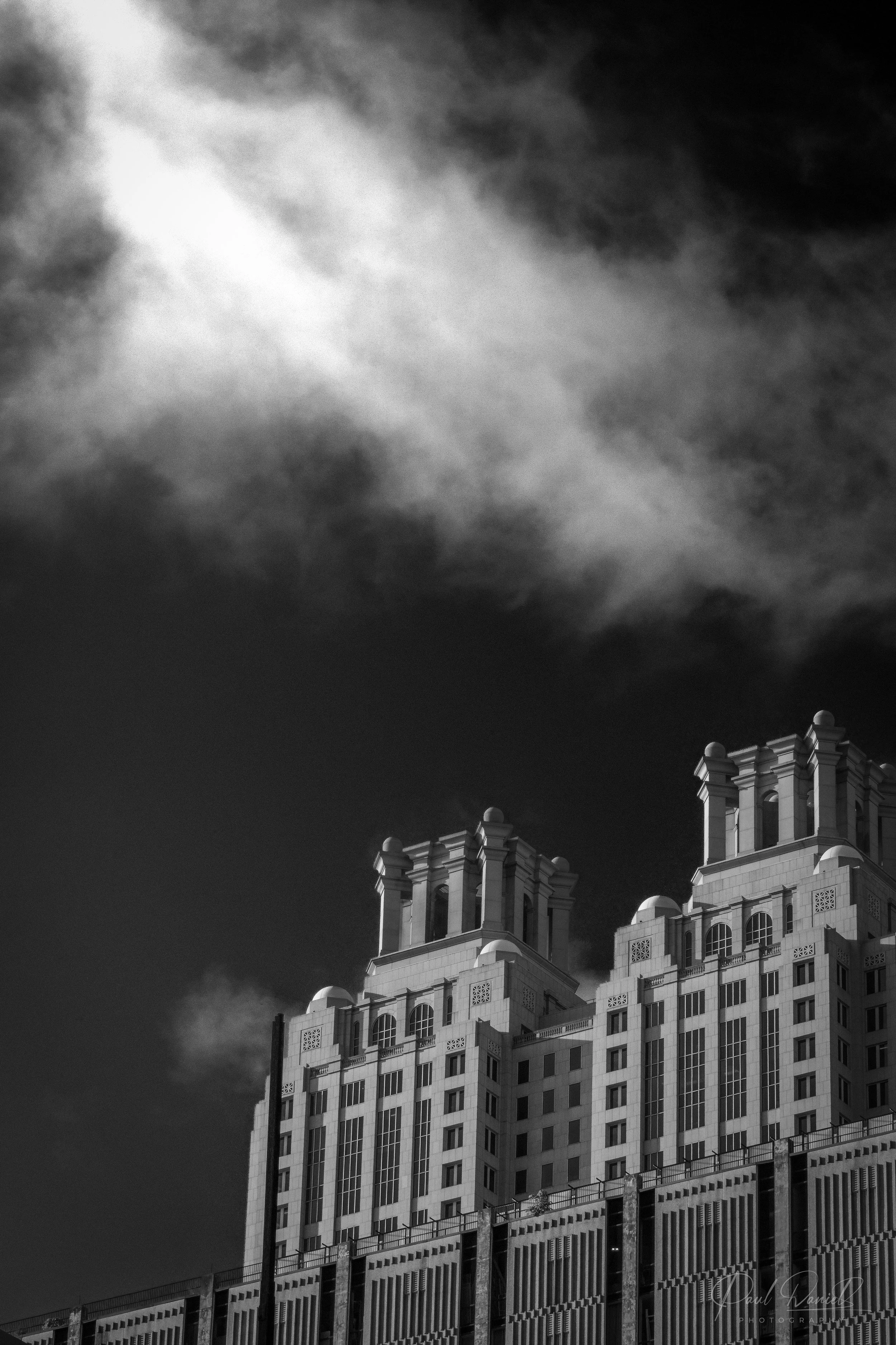 Black and white fine art photography of the twin rooftop crowns of 191 Peachtree Tower under dramatic clouds in Downtown Atlanta