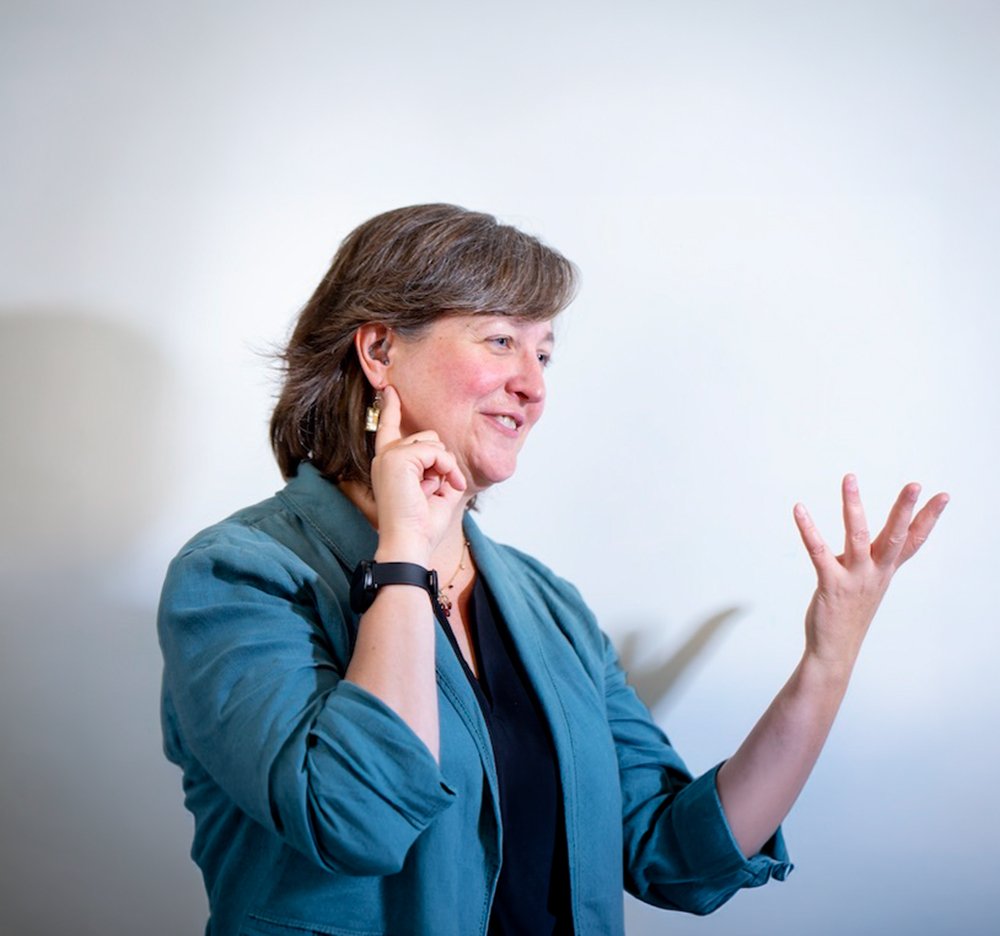 Michele Cooke signing "deaf" against a white background