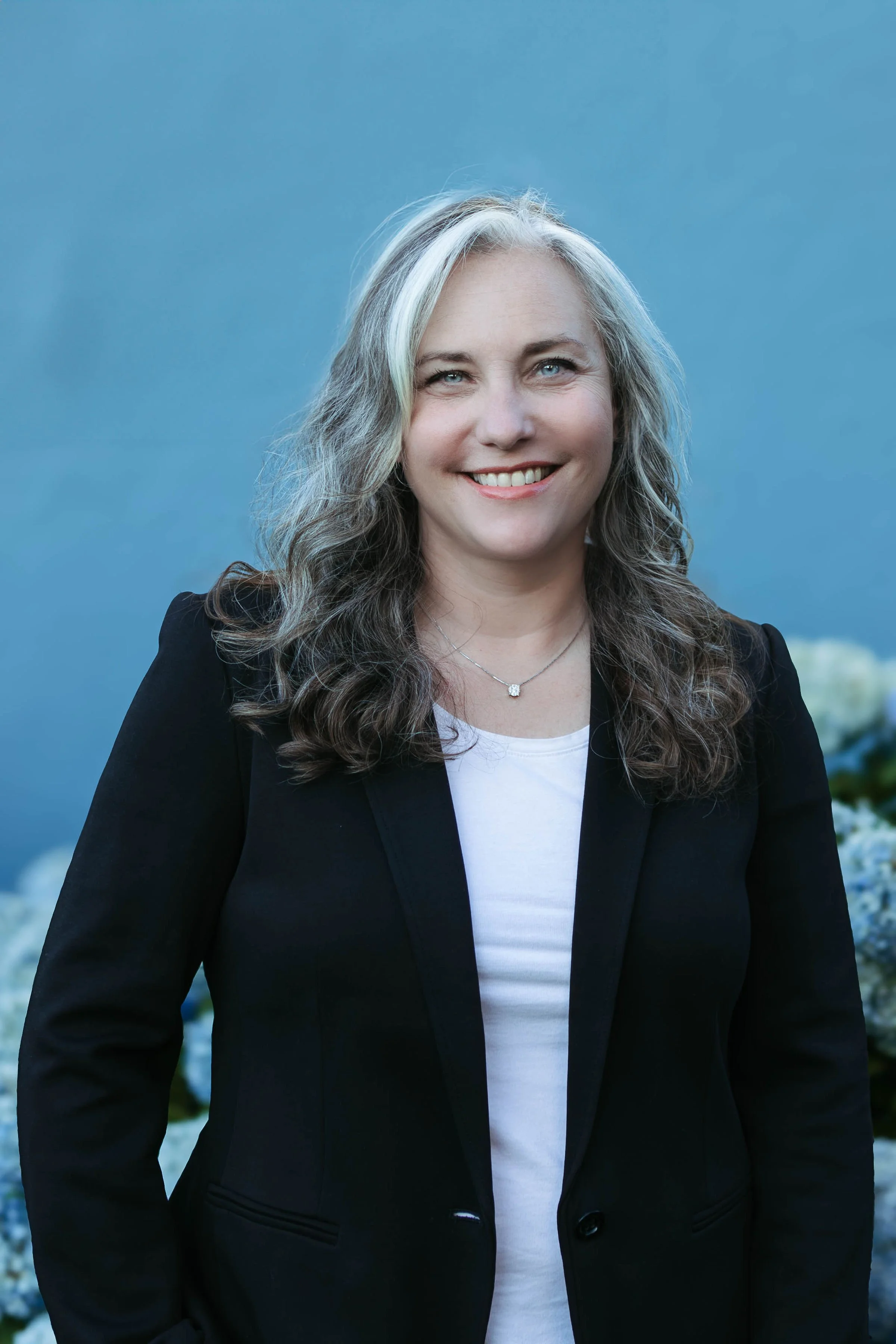 photograph of woman with a blue background wearing a blazer