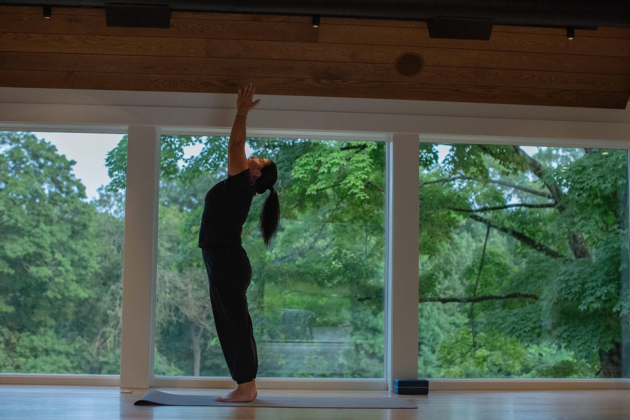 A woman performing a yoga pose on a mat surrounded by nature