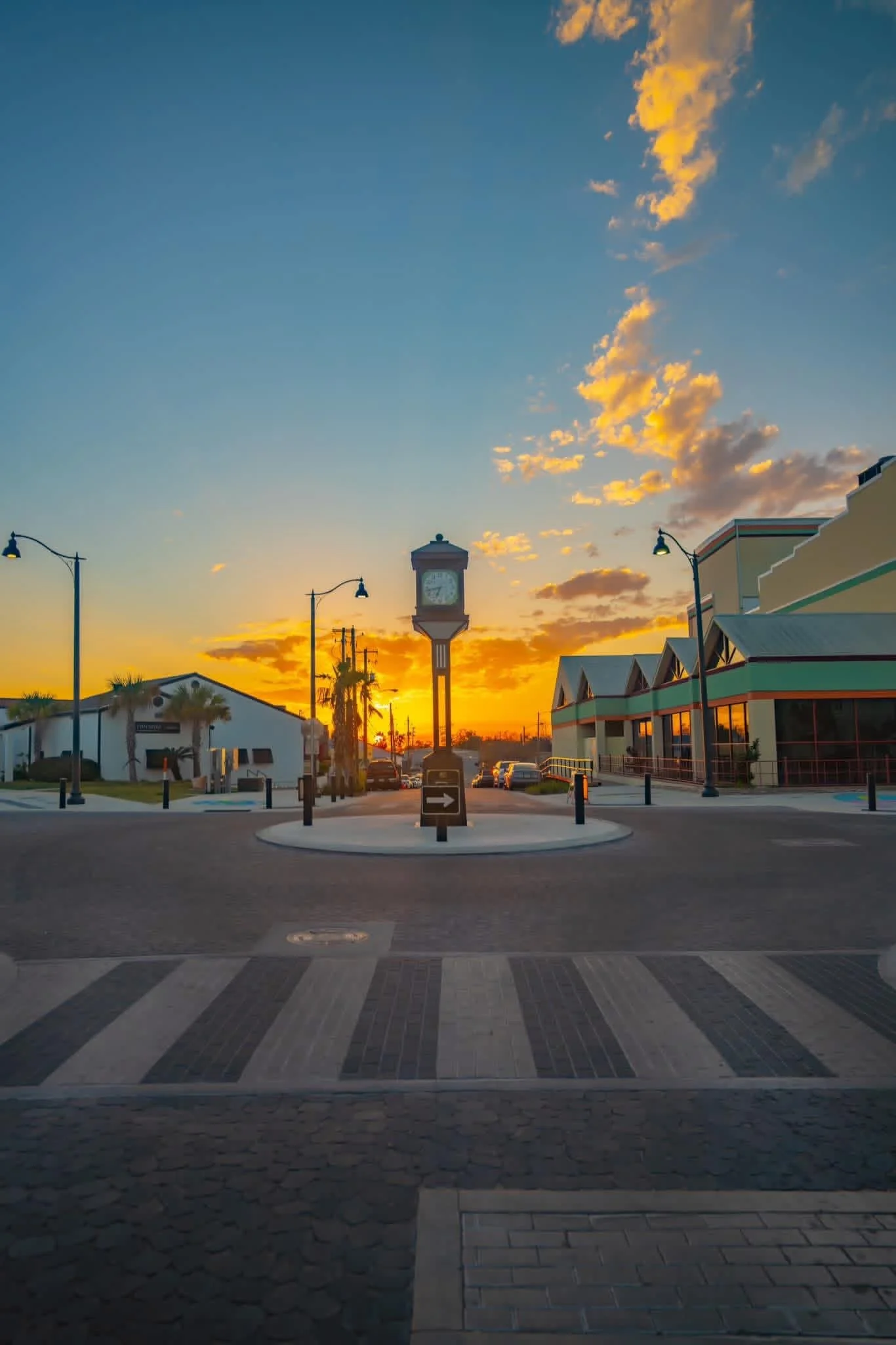 Downtown Panama City, Florida streetscape at sunset with historic clock tower, palm trees, and pedestrian crosswalk.