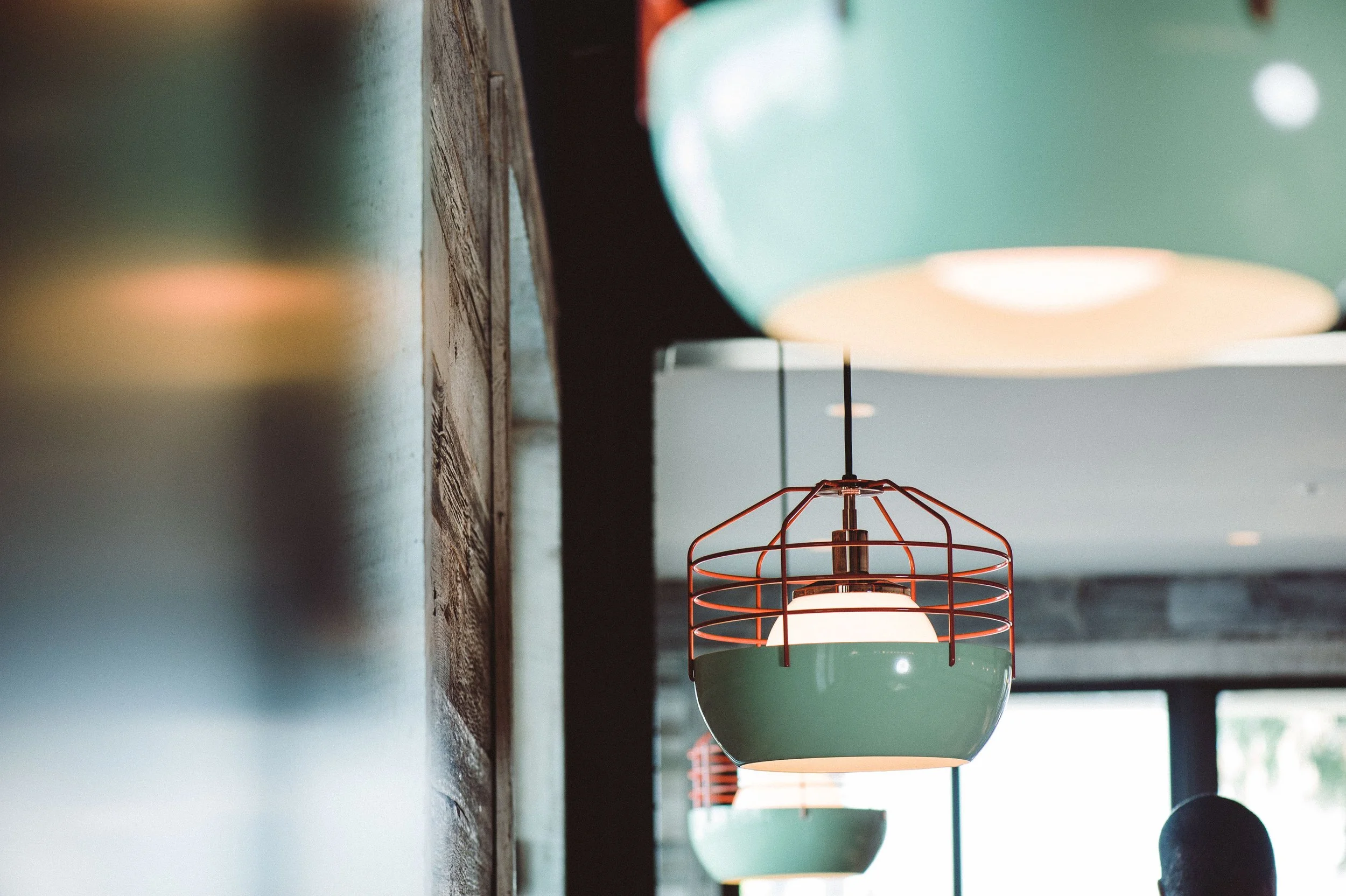 Close-up of hanging pendant lights with pastel-colored shades in a modern interior.