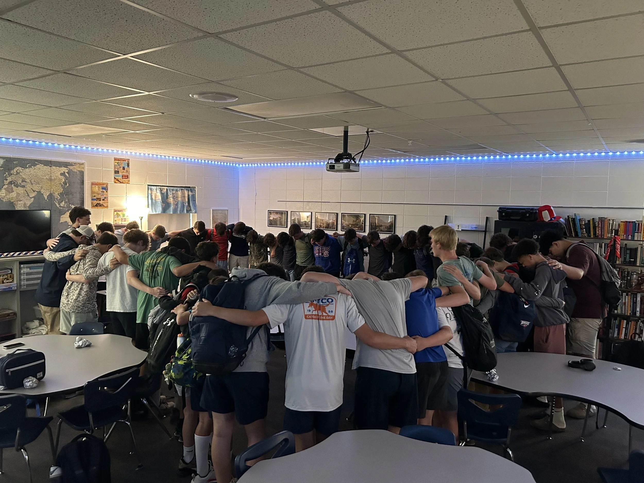Students in a classroom bowing their heads and praying.