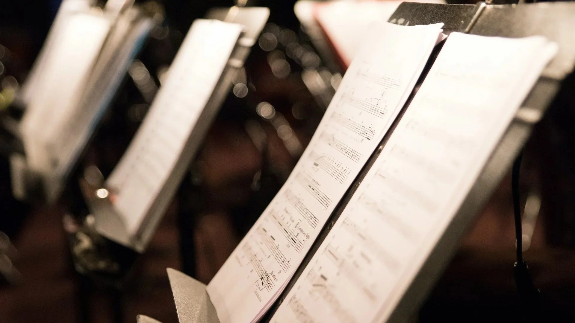 A photograph of a row of three music stands with sheet music.
