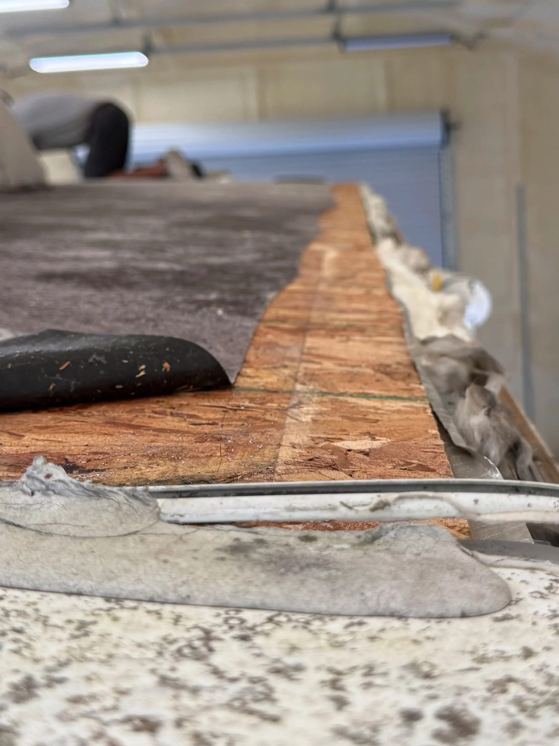 Close-up of a mosaic tile in a bathroom with a black object and rocks on the surface, seen from a low angle near the edge of the tile.