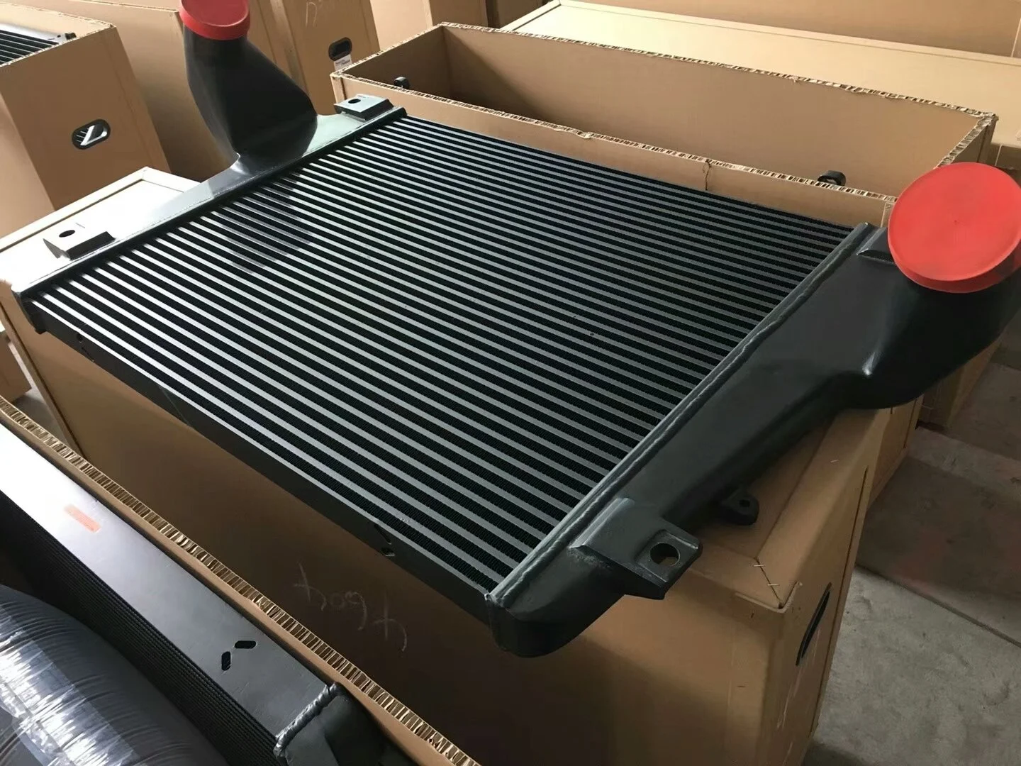 Large black radiator in bar & plate structure on a wooden pallet, by Karaxes Industries, in a warehouse setting.