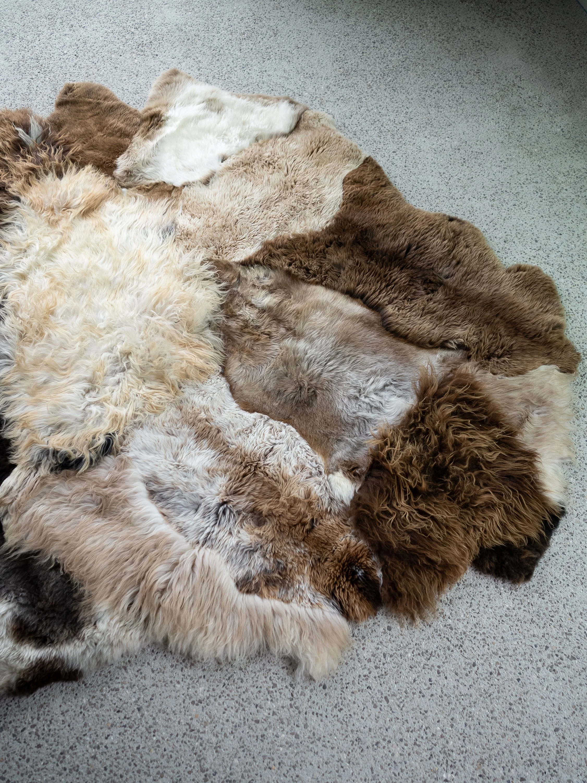 Breezy by Wol Society, a patchwork sheepskin rug in chocolate, taupe and frosted grey with one brown-and-white pelt