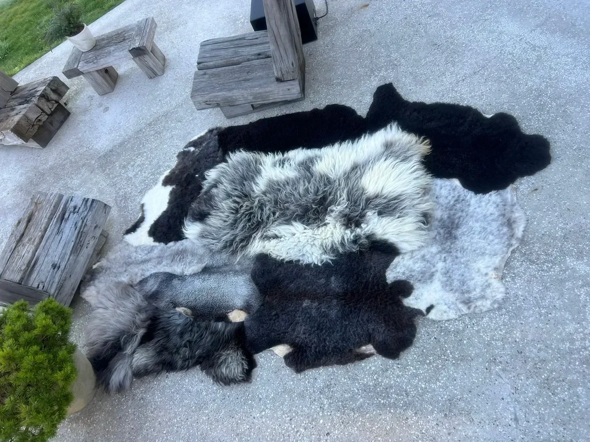 Dotje is a black and grey patchwork sheepskin rug (102 x 67 in.) with black, charcoal and silver pelts around a shaggy white-and-grey center.