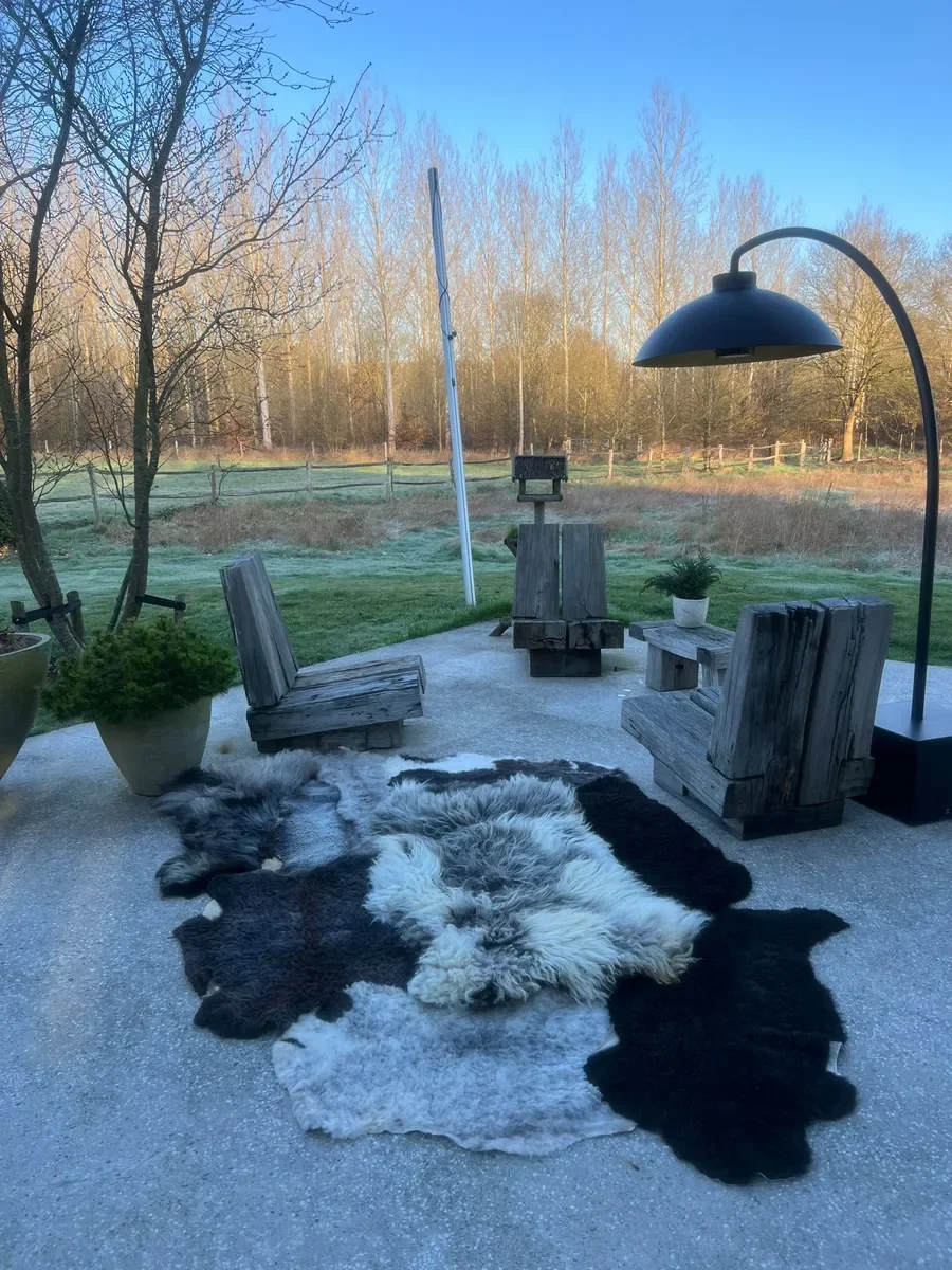 Dotje is a black and grey patchwork sheepskin rug (102 x 67 in.) with black, charcoal and silver pelts around a shaggy white-and-grey center.