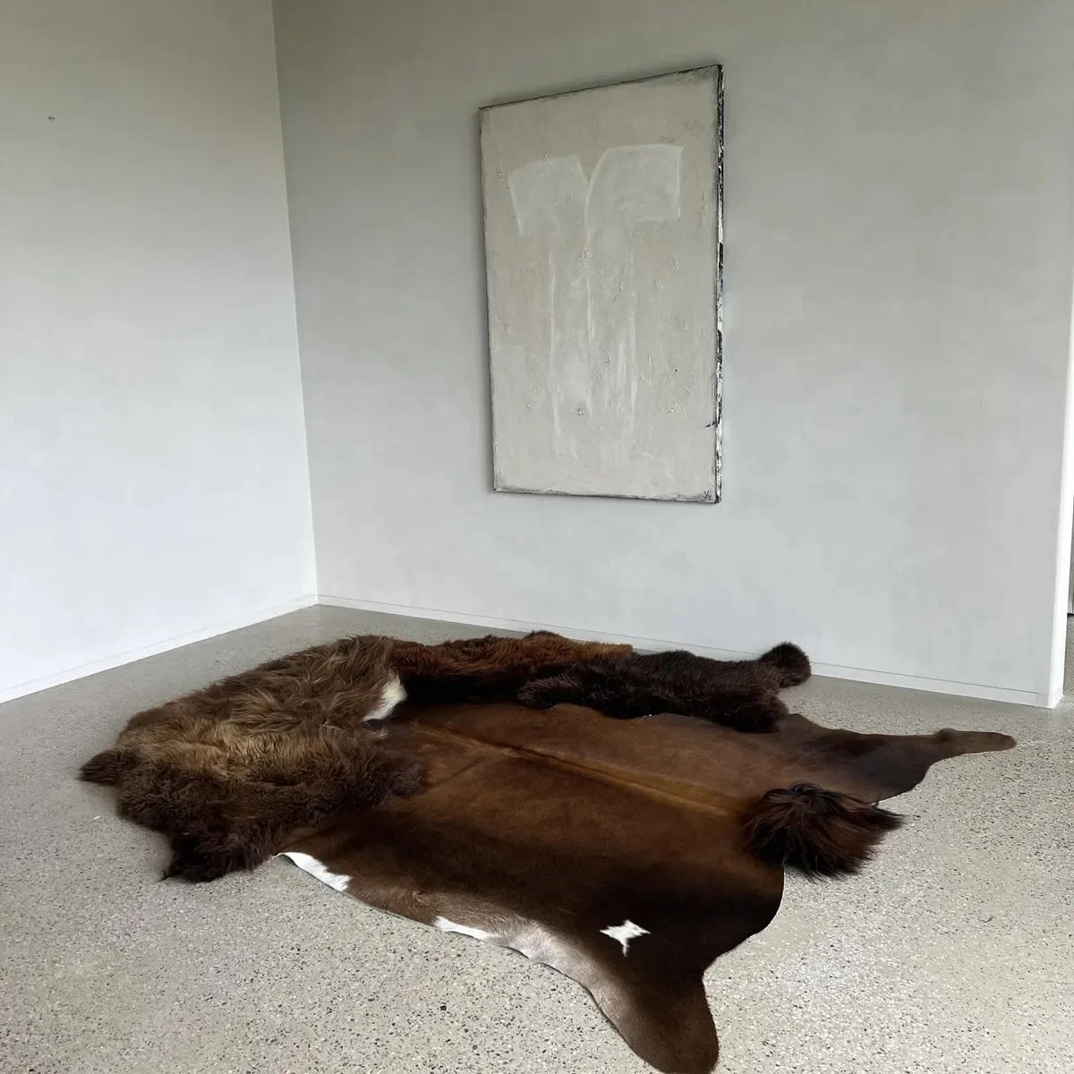 Chili by Wol Society, a brown rug with a glossy chocolate cowhide center ringed by long, dark sheep skin