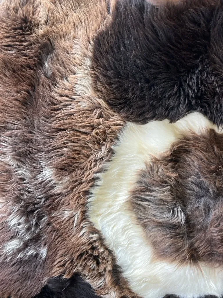 Titan by Wol Society, a dark brown sheepskin rug with a swirl of white at its center