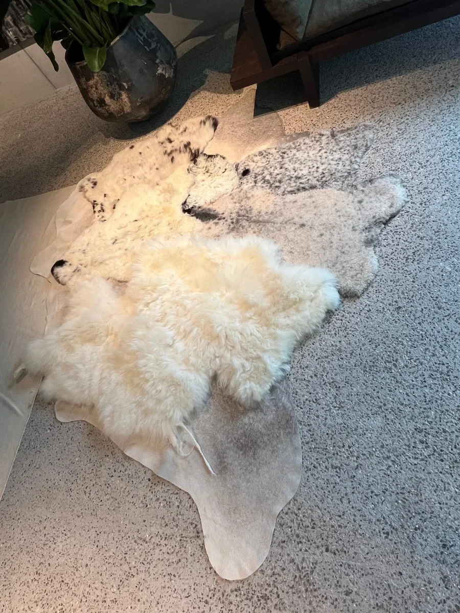 Mieke 206 by Wol Society, a cream sheep skin rug with speckled black and white pelts on a pale grey cowhide border