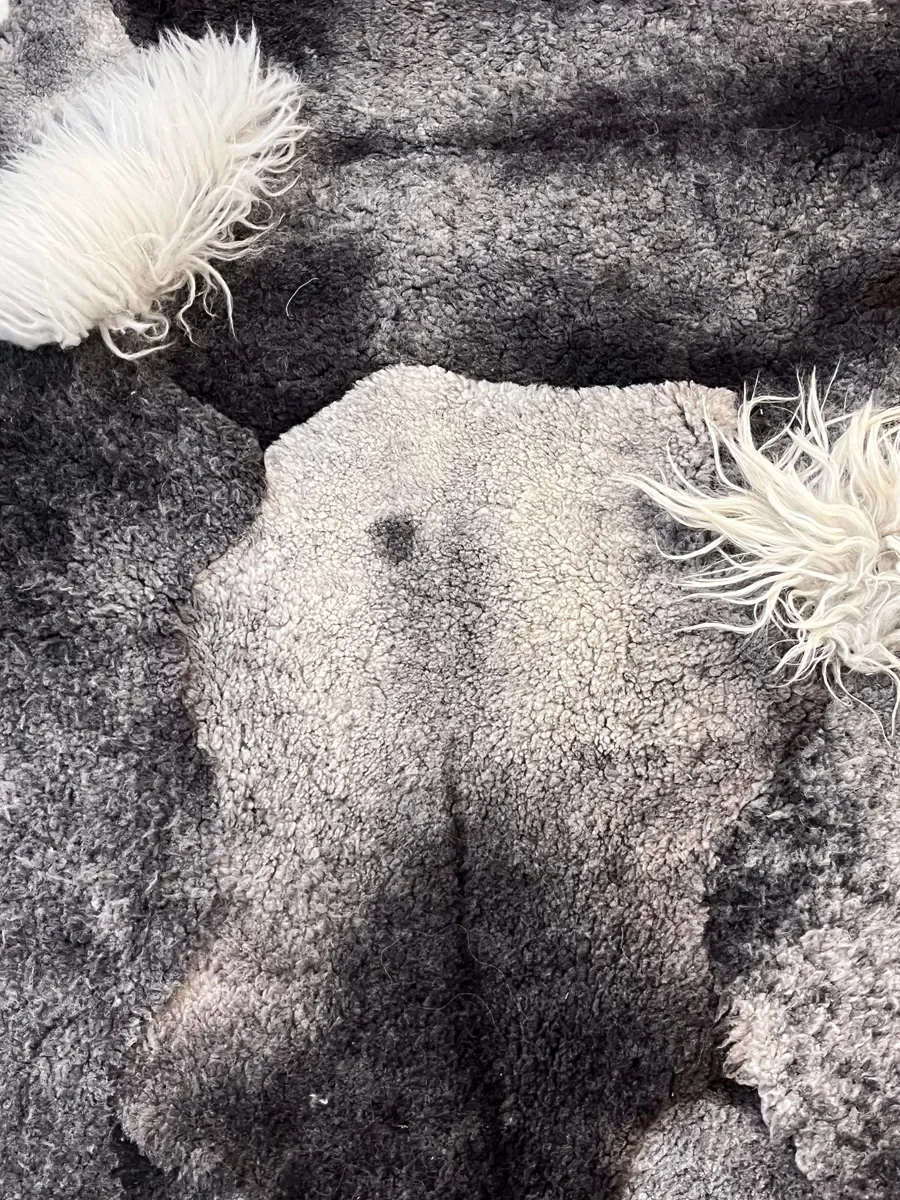 Piece Unique by Wol Society, a charcoal and silver grey Gotland lambskin carpet with tufts of white curls