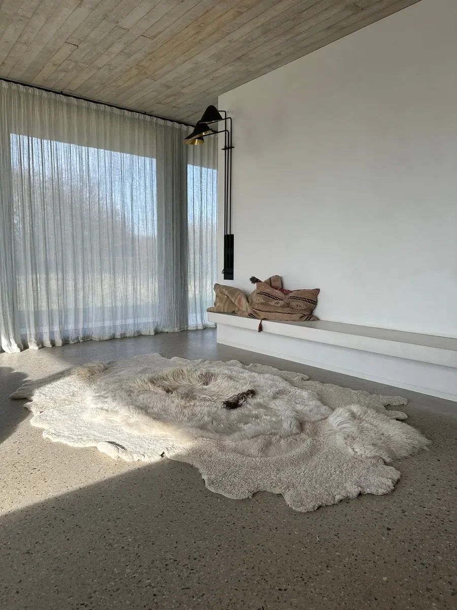 Jules by Wol Society, an ivory sheep skin rug with curly edges and one dark brown accent at its center