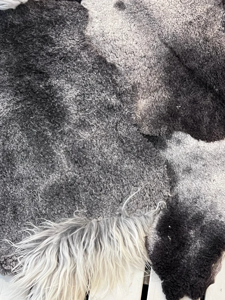 Piece Unique by Wol Society, a charcoal and silver grey Gotland lambskin carpet with tufts of white curls