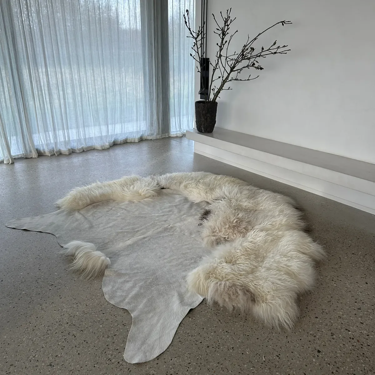 Easy by Wol Society, a pale grey cowhide rug edged with long, fluffy creamy white sheepskin