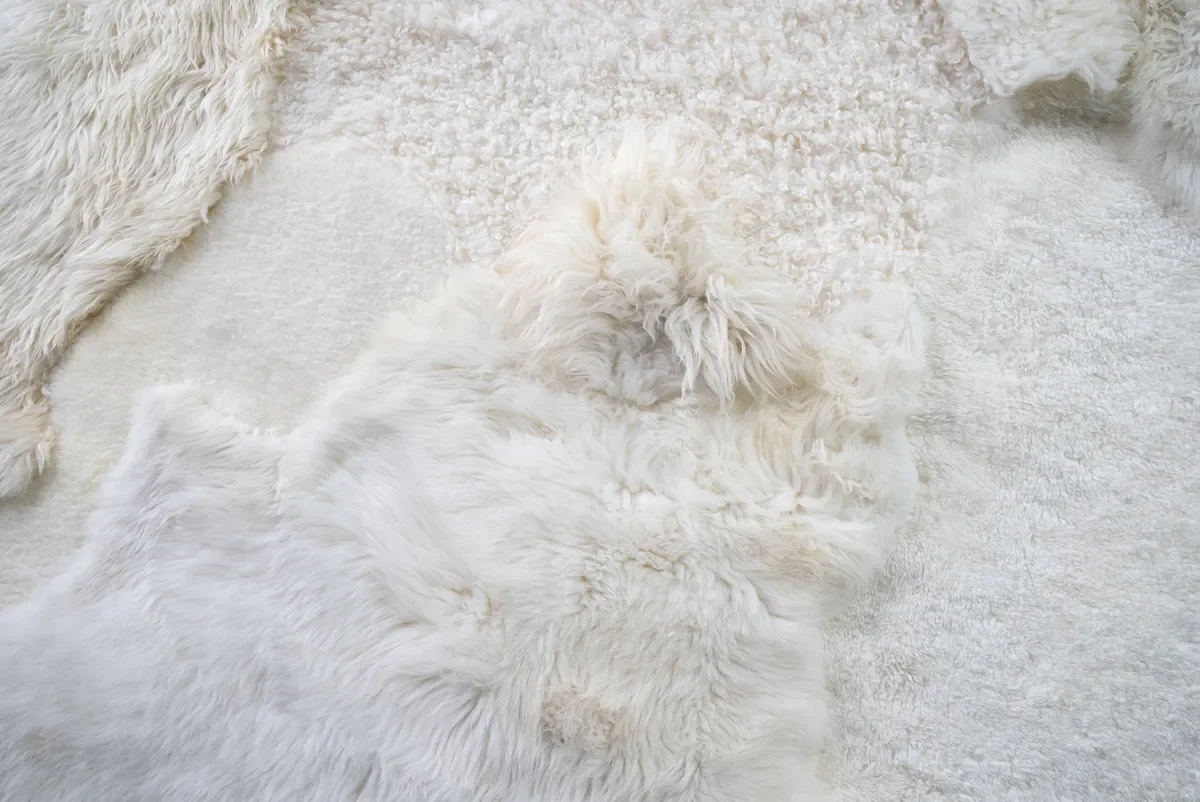 Sjoe by Wol Society, a near-square white sheepskin rug with smooth, curly and fluffy patches