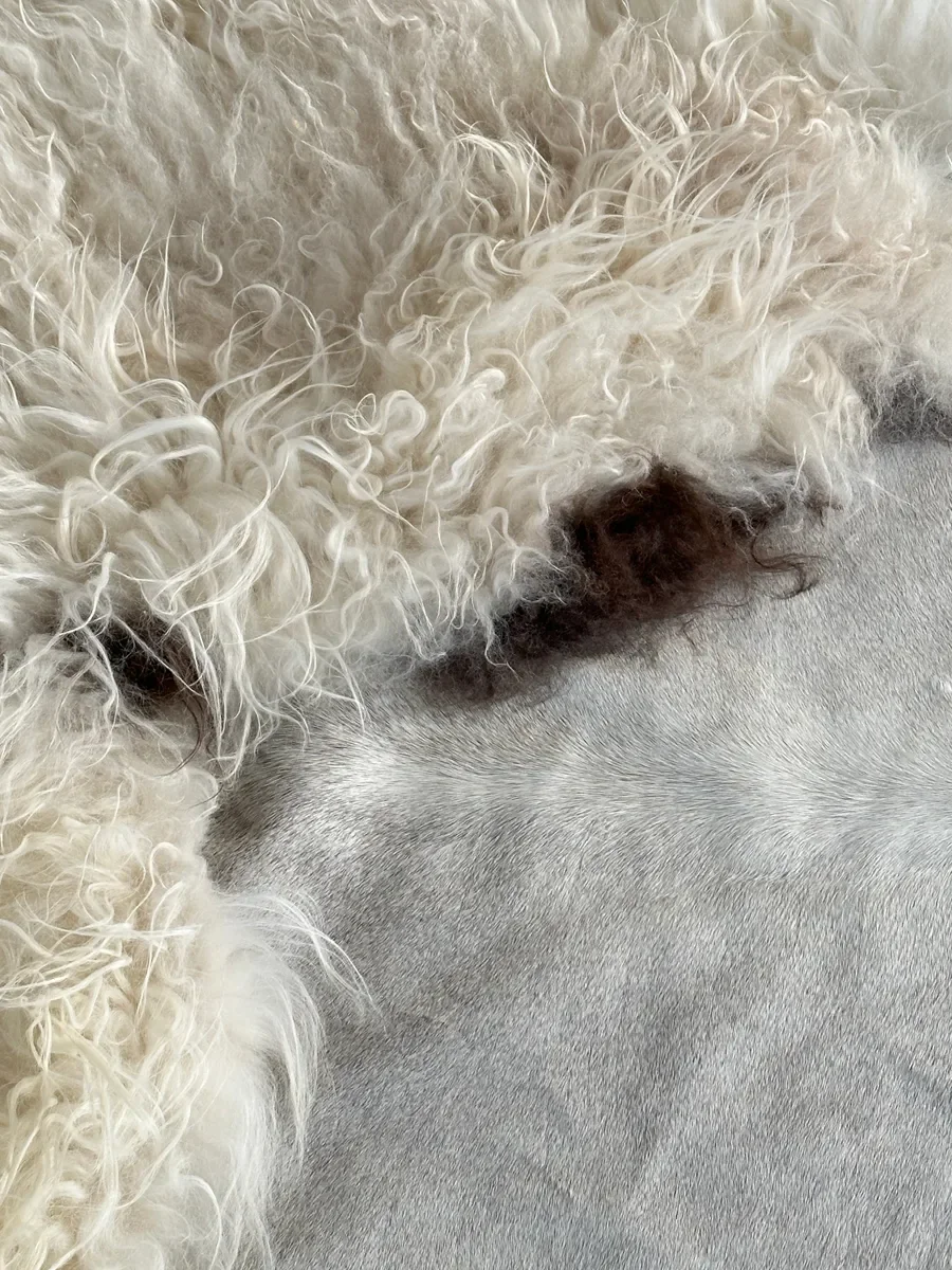 Easy by Wol Society, a pale grey cowhide rug edged with long, fluffy creamy white sheepskin