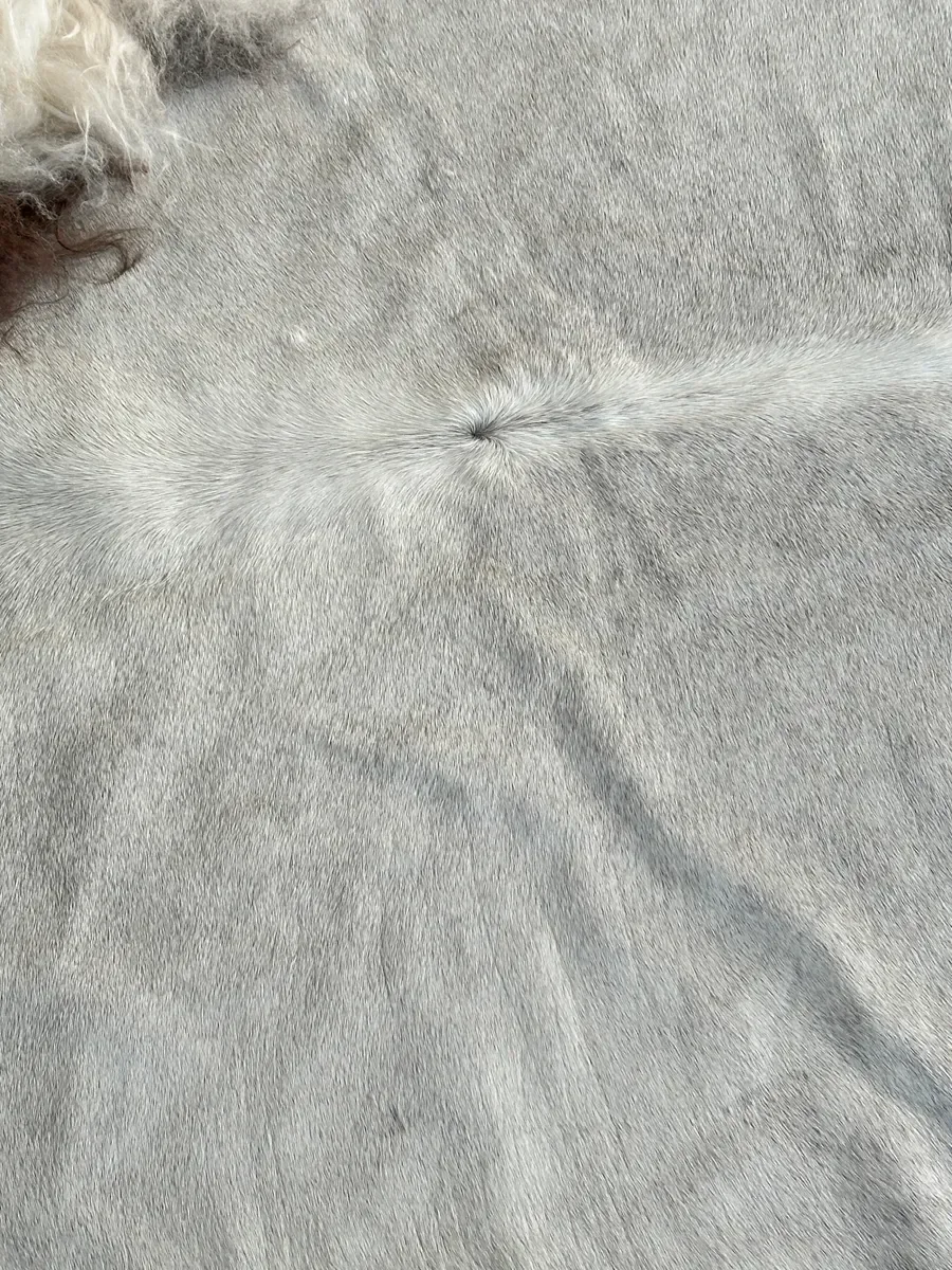 Easy by Wol Society, a pale grey cowhide rug edged with long, fluffy creamy white sheepskin
