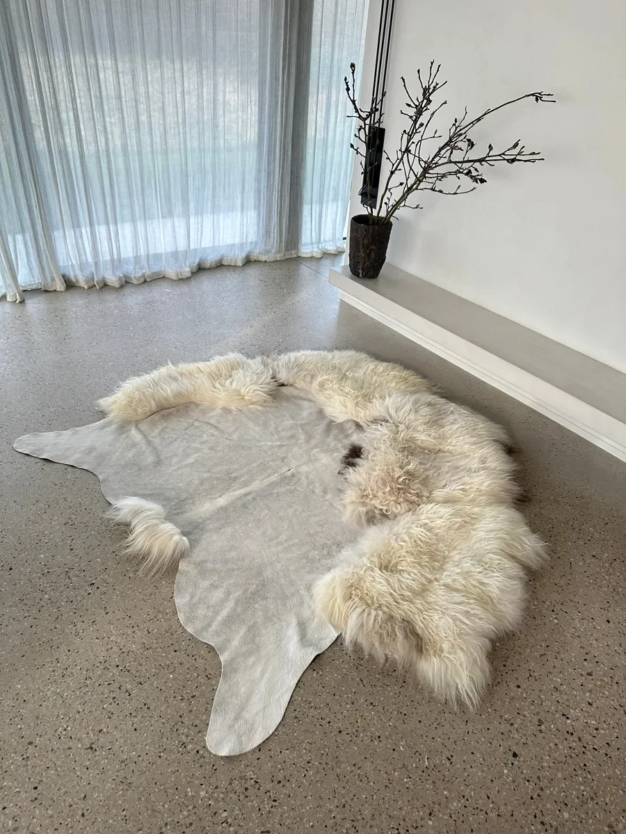 Easy by Wol Society, a pale grey cowhide rug edged with long, fluffy creamy white sheepskin